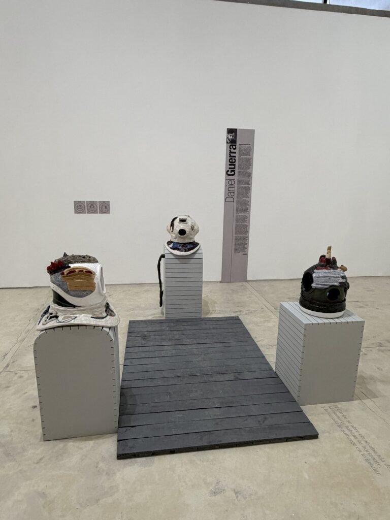 Obra Archipiélago sensorial del Caribe de Daniel Guerra: tres piezas escultóricas sobre pedestales grises y una plataforma de madera oscura en la sala de exposición